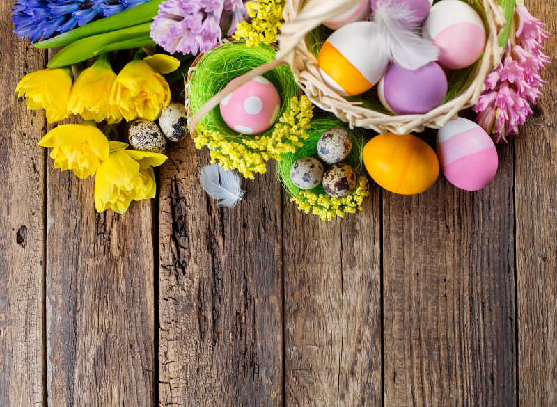 木板上的篮子里的复活节彩蛋和花朵