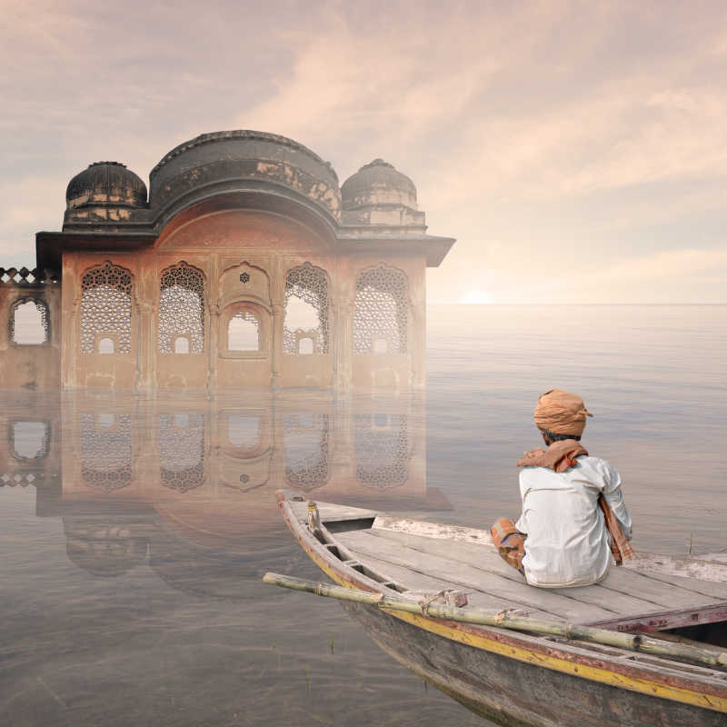坐在湖面船上的印度男性看着印度建筑