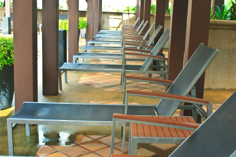 泳池旁陈列一排带扶手的休闲躺椅