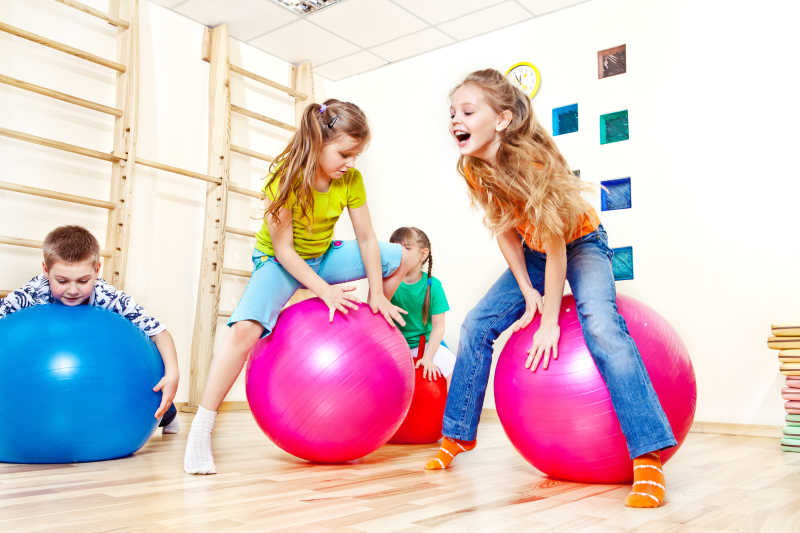 一群活泼的孩子在健身房跳体操球