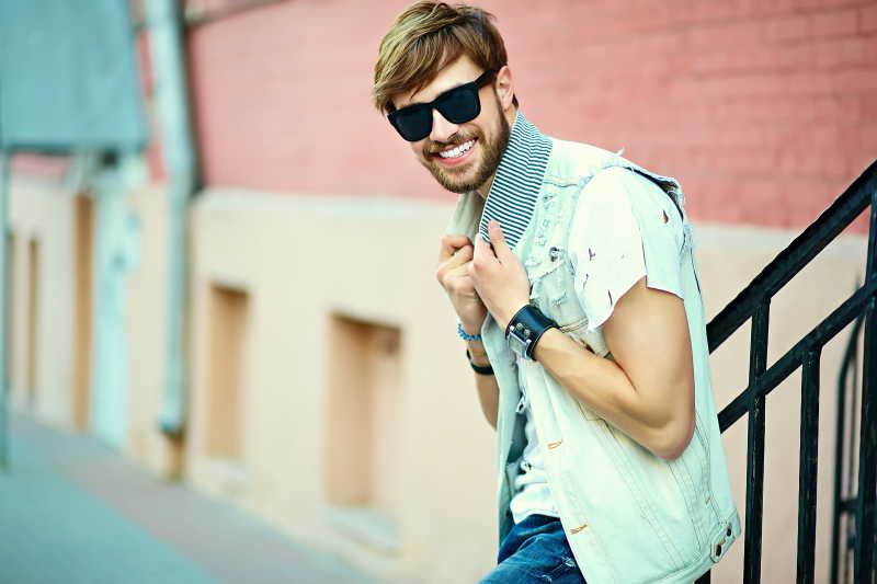 夏在街上天带着时尚太阳镜滑稽的微笑的时髦帅哥