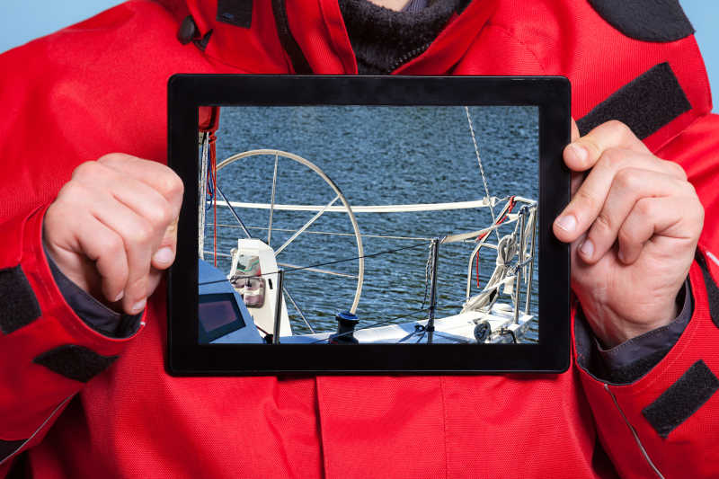 男性双手捧着iPad展示游艇帆船照片特写