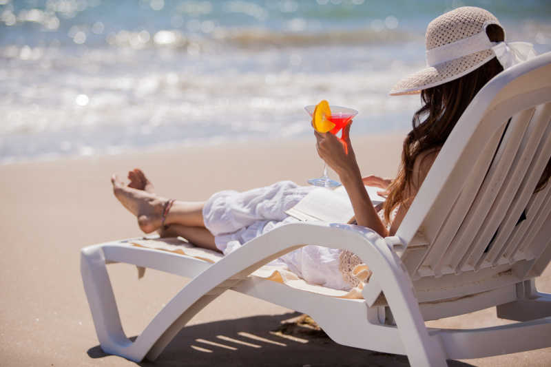 沙滩椅拿着饮料放松的女子