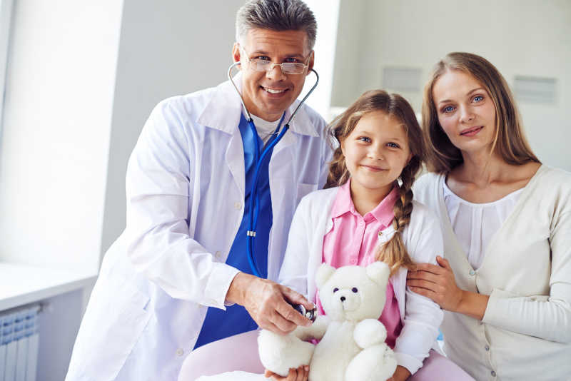 儿科医生和抱着玩具熊的小女孩及母亲