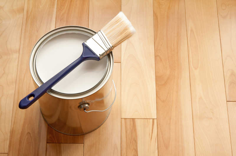木地板上的油漆刷和白色油漆罐