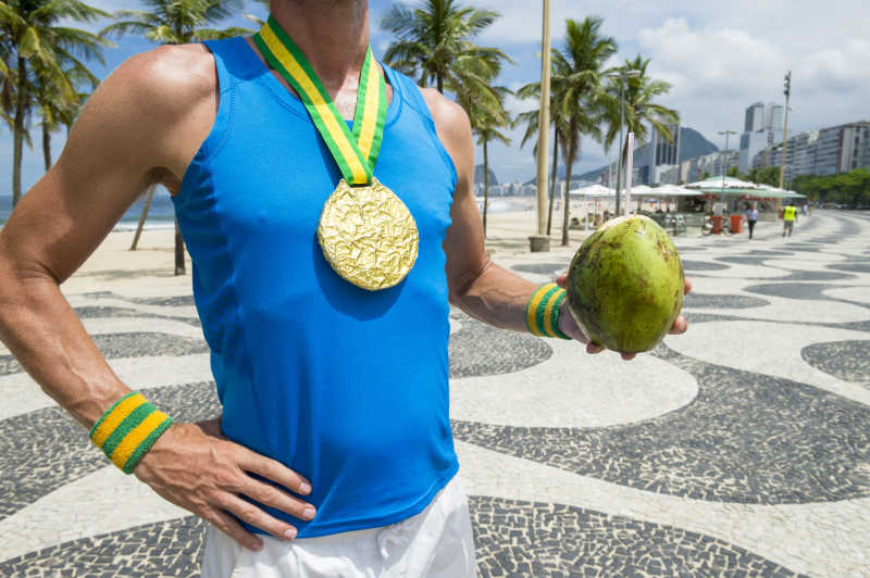 沙滩上手拿椰子的金牌运动员