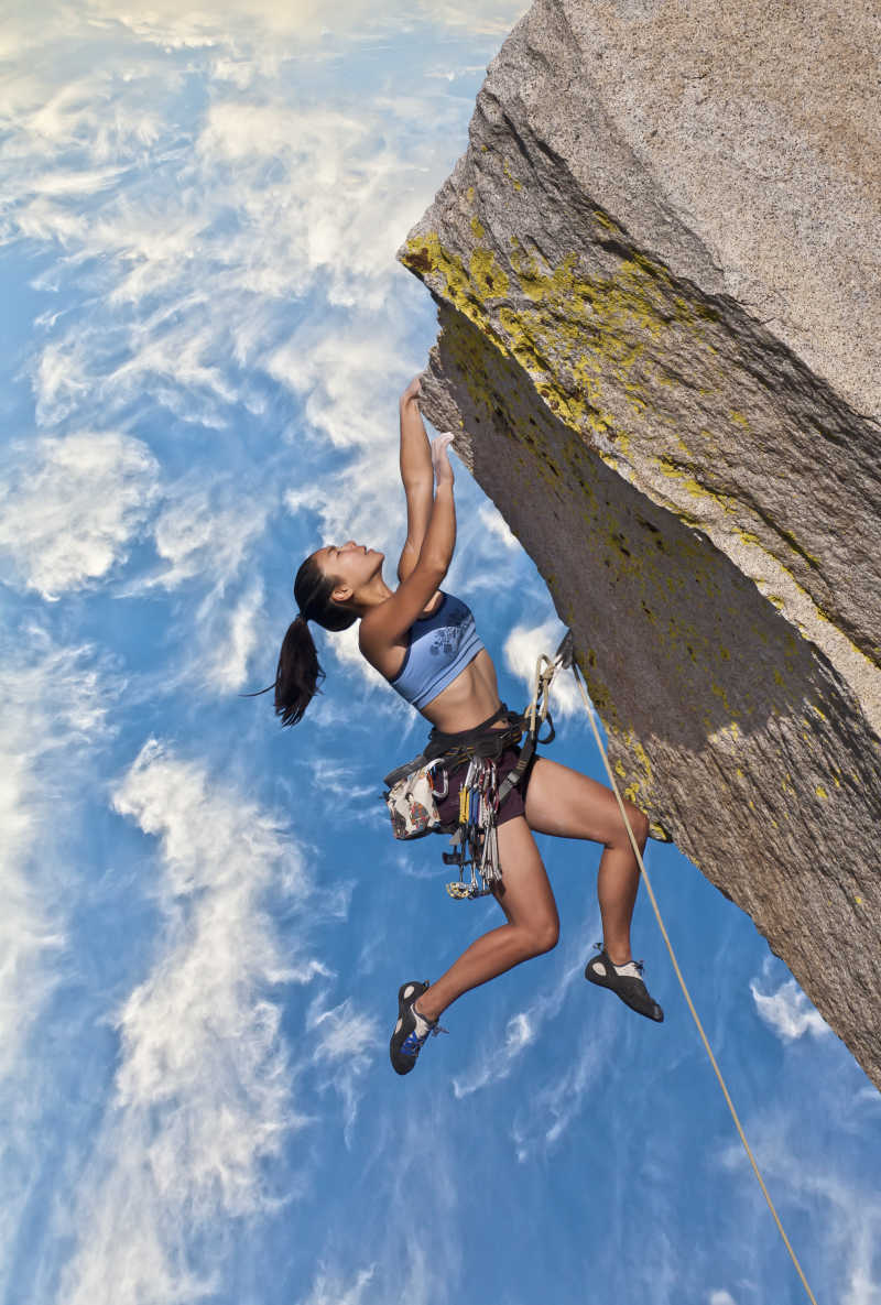 女攀岩者挣扎在具有挑战性的悬崖边上挣扎着
