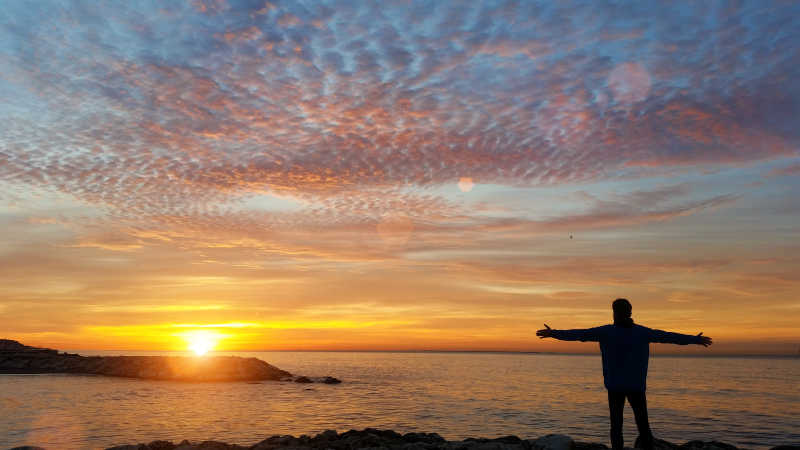 男人站在海边看着日出