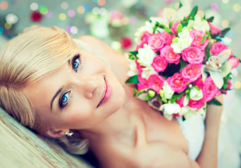 美丽的金发新娘捧着一束鲜花