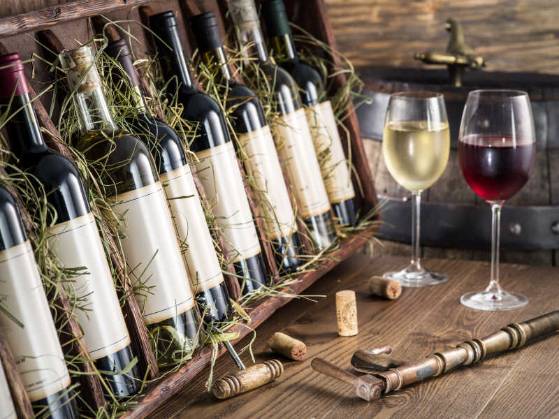 桌上陈列的一排葡萄酒瓶和倒好的两杯白葡萄酒和红葡萄酒