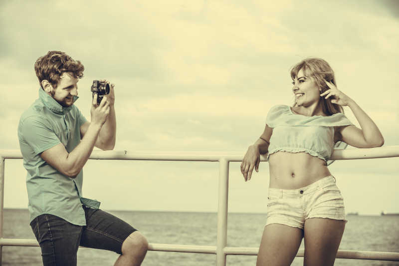 相爱的年轻情侣在码头上拍照