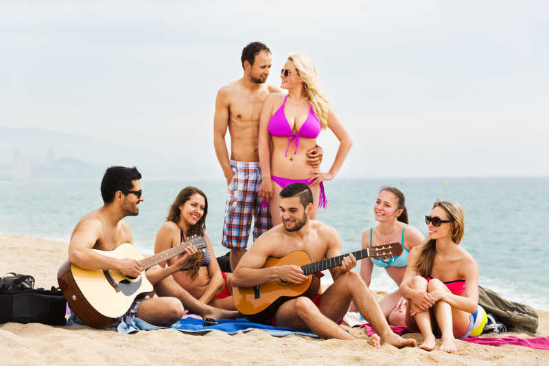 成年人与吉他放松在沙滩上