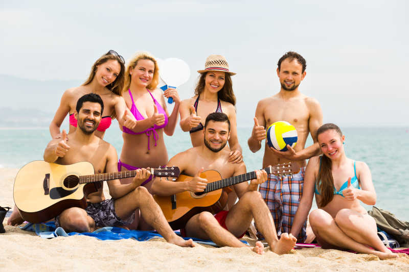 快乐的一群朋友在沙滩上弹吉他
