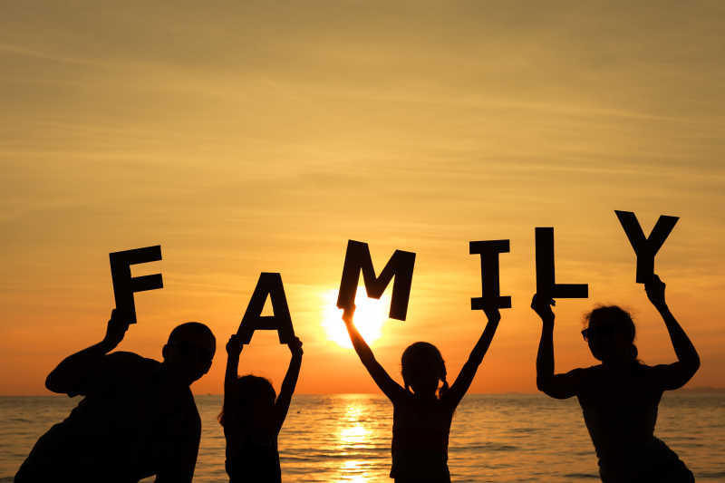 日落时分站在海滩上的幸福家庭
