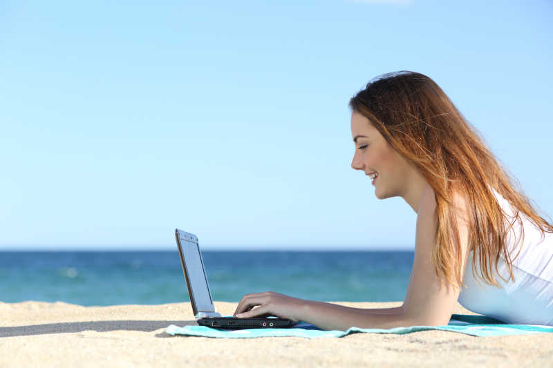 少女在海滩上浏览笔记本电脑