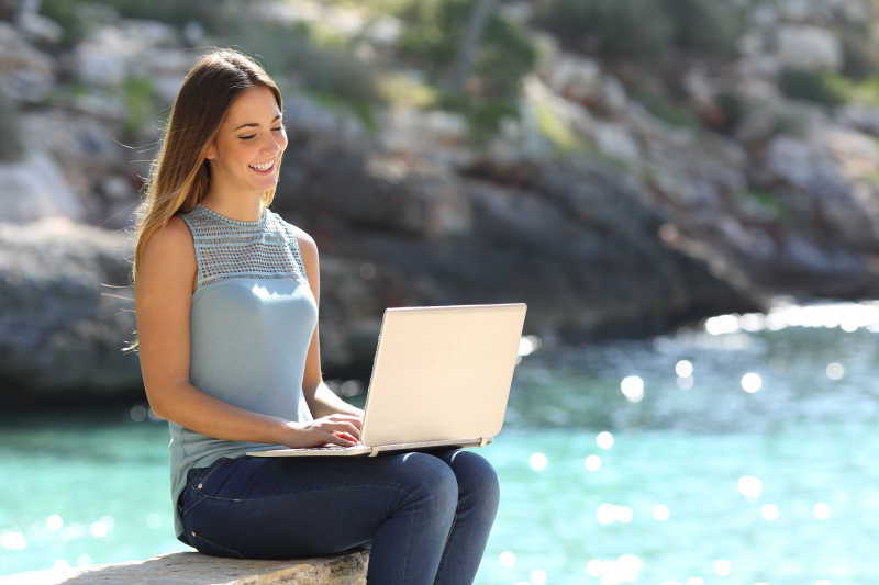 在热带海滩上用手提电脑打字的女人