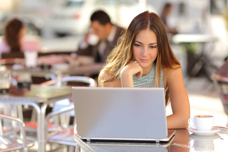 女人在咖啡店里的笔记本电脑上看媒体