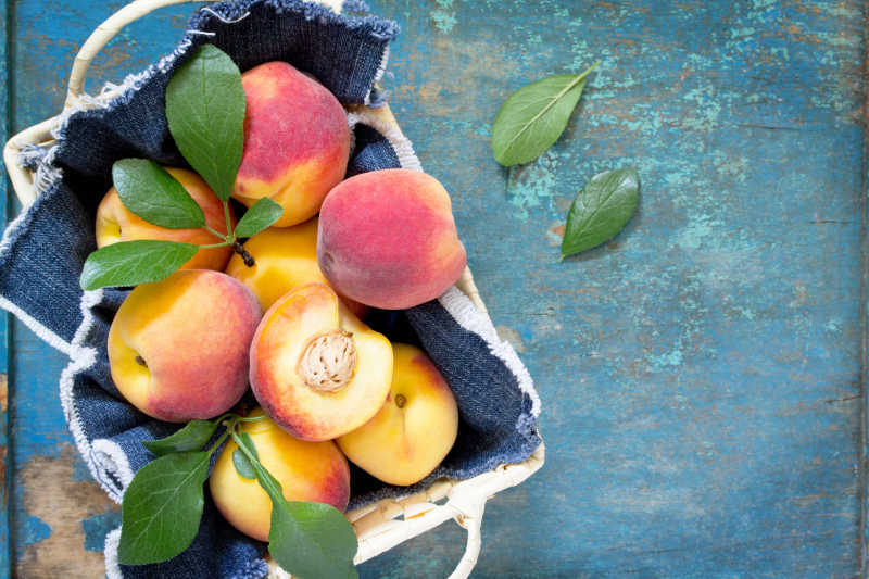 在古老的木桌上用柳条筐收获新鲜成熟的桃子