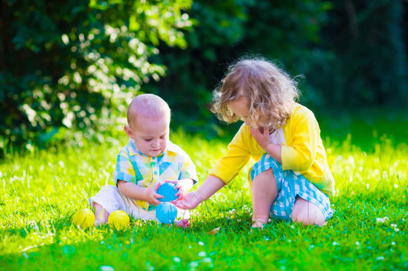 在草坪上玩球的小男孩与小女孩