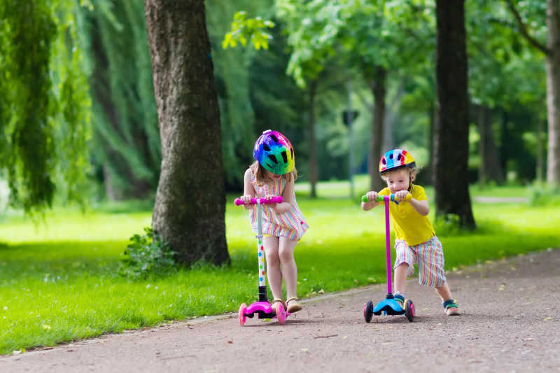 孩子们在公园里学骑滑板车