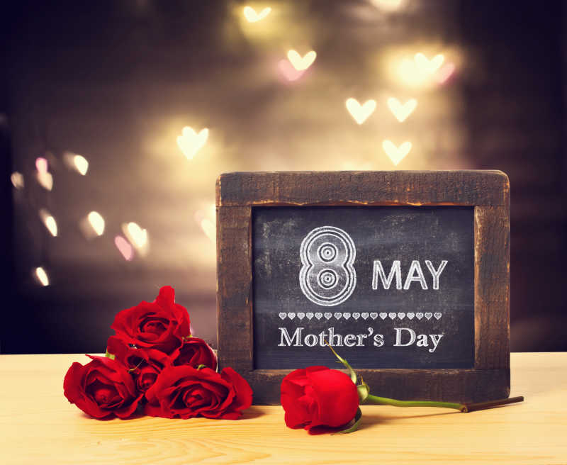 小黑板上5月8日母亲节提示语和桌上的红玫瑰