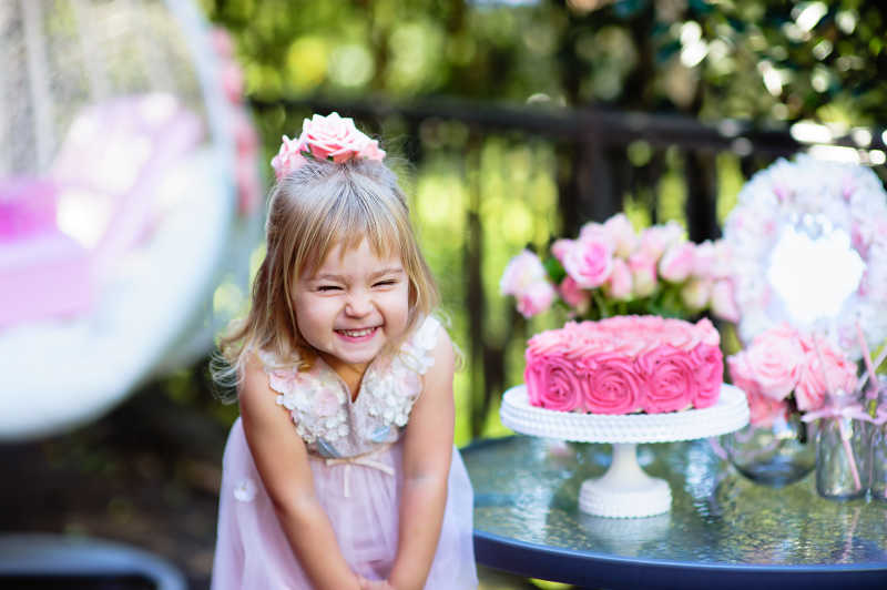 粉色玫瑰旁灿烂微笑的小女孩