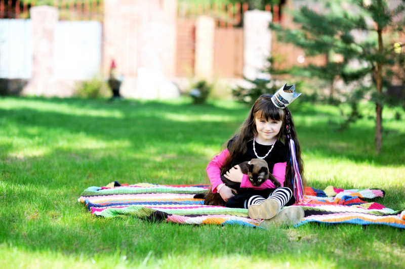 小女孩抱着缅甸猫在草坪玩耍