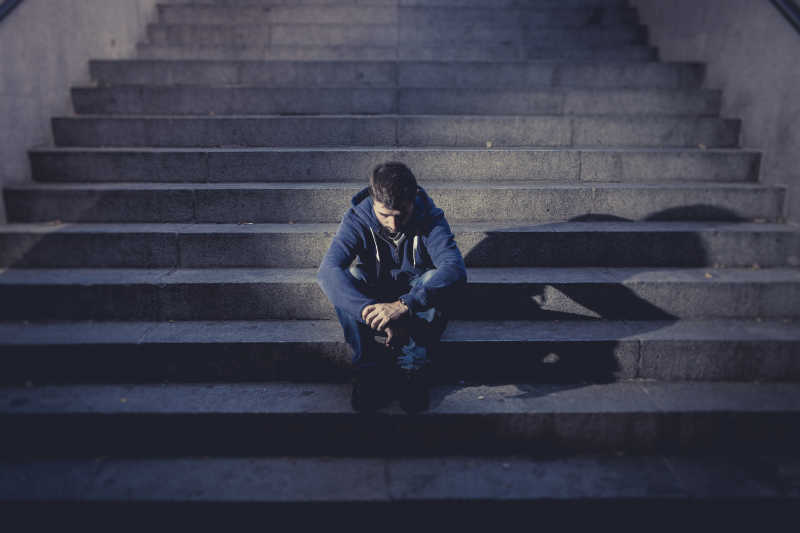 年轻的男子坐在水泥楼梯上