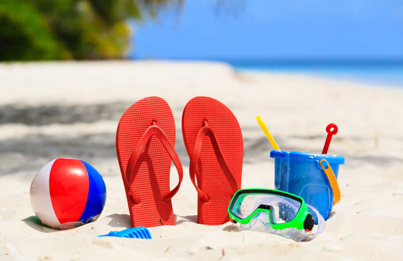 沙滩上有红色拖鞋和各种玩具