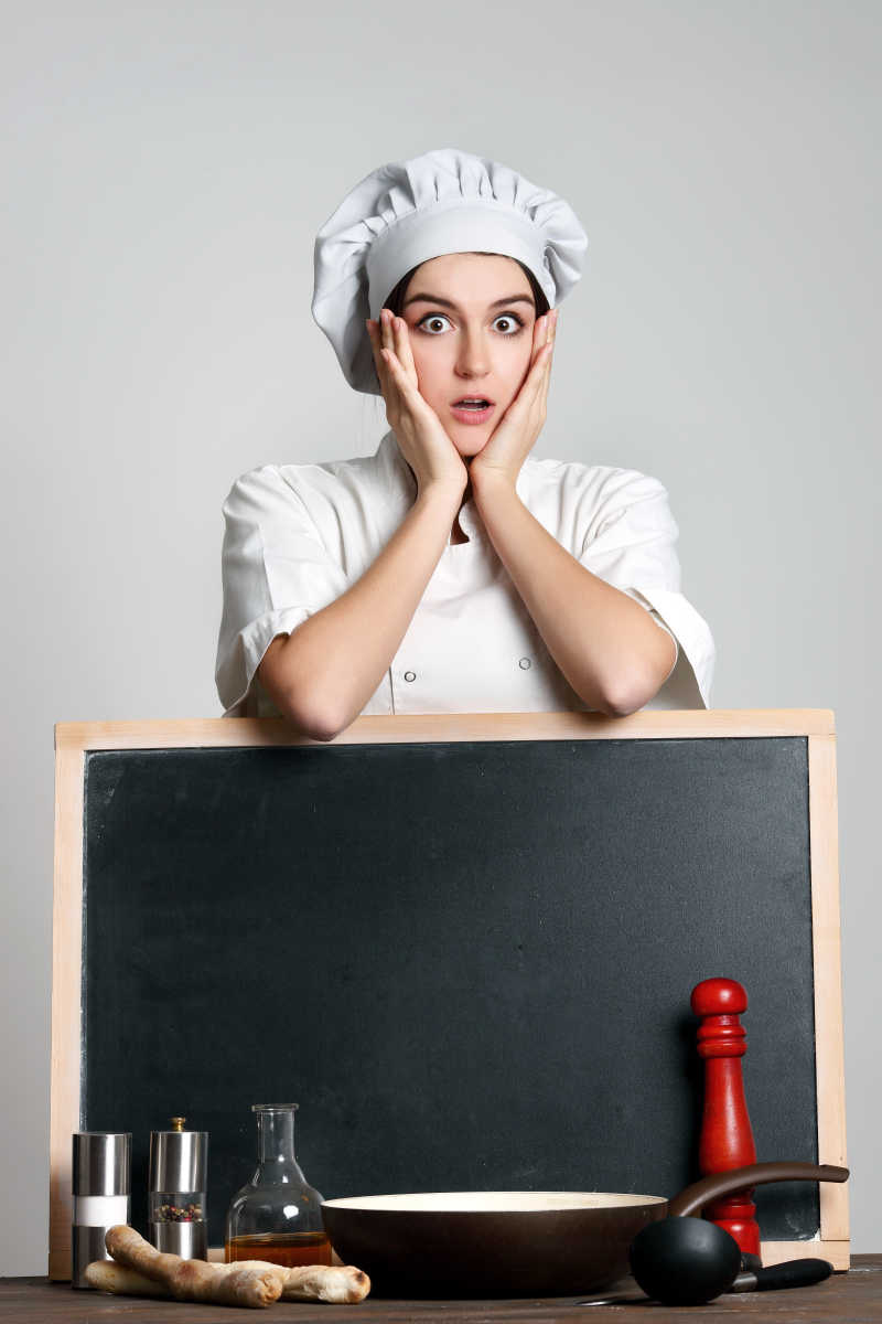 女厨师抱着广告牌露出惊讶的表情