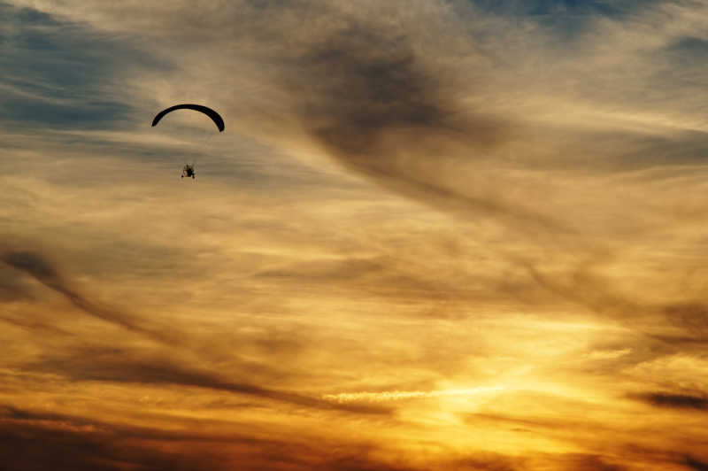 滑翔伞在云日落下