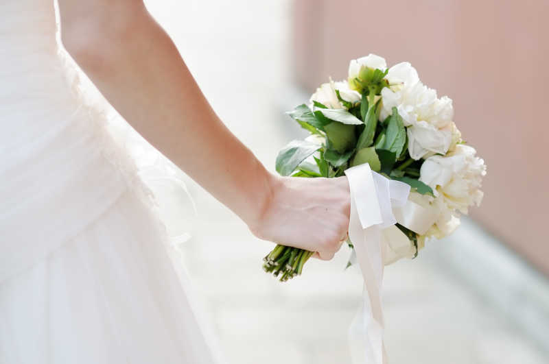 白婚纱新娘拿着白色的鲜花