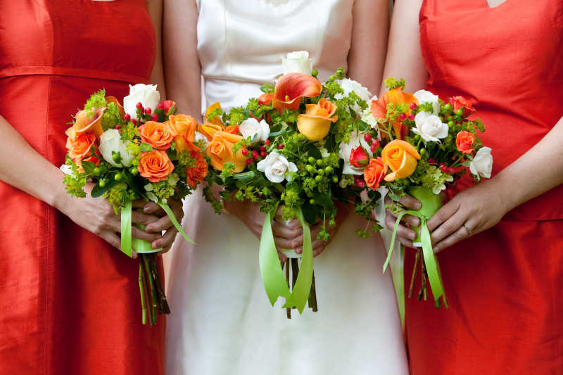 白衣新娘和红衣伴娘手拿鲜花