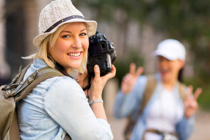 快乐的年轻游客用数码相机拍朋友的照片