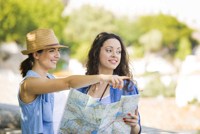 两个美丽的女游客在地图上寻找一个地方