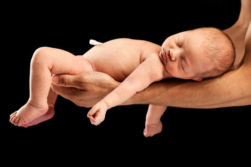 刚出生的婴儿躺在男人的手臂上