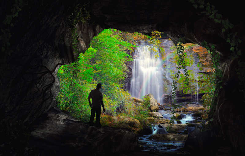 一个人在洞口欣赏美丽的瀑布景色