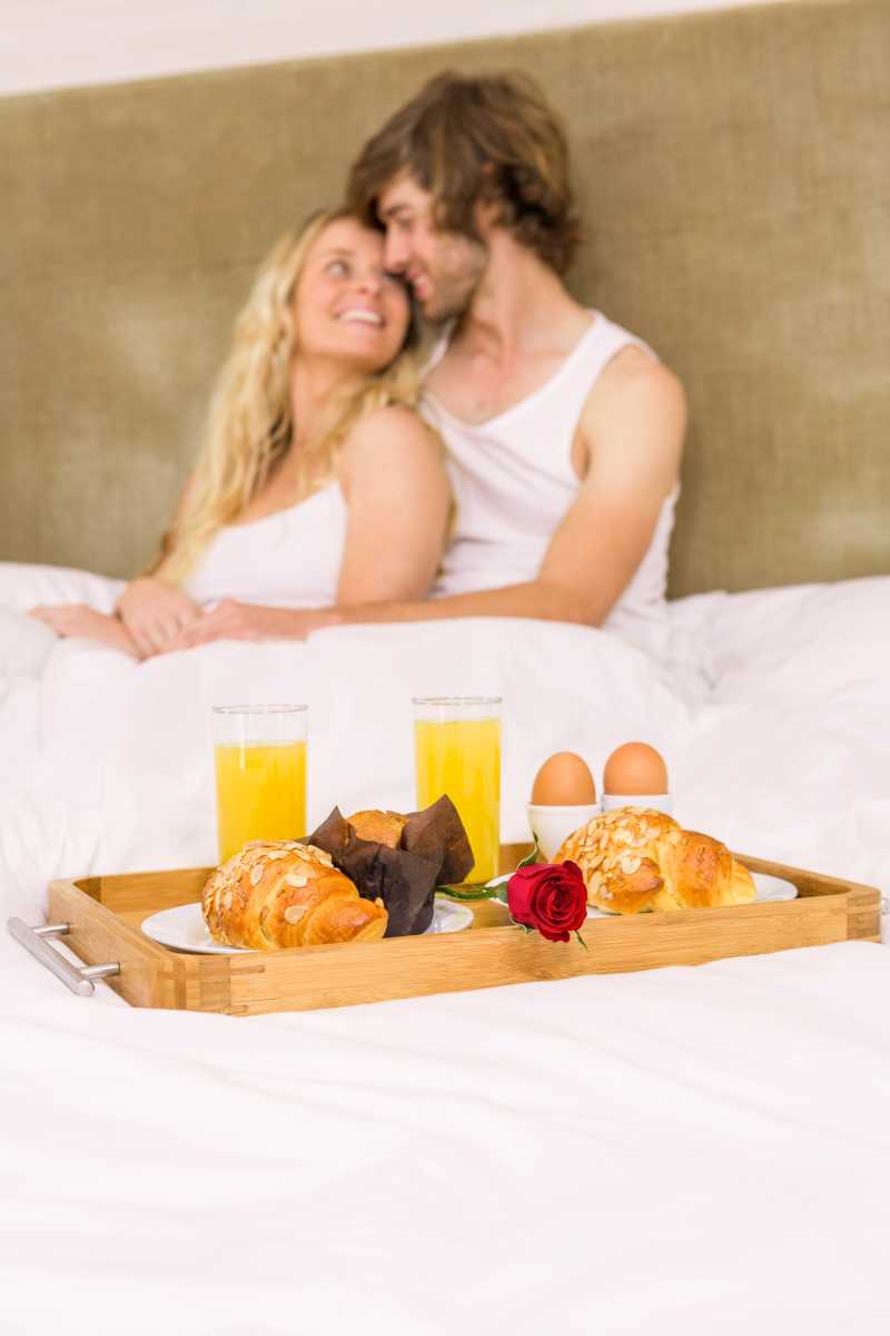 床上依偎在一起的情侣和早餐