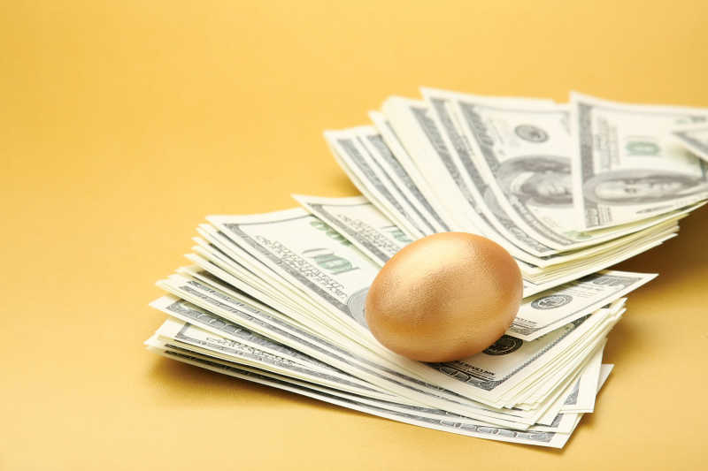 黄贝桌面的美元纸币与金蛋