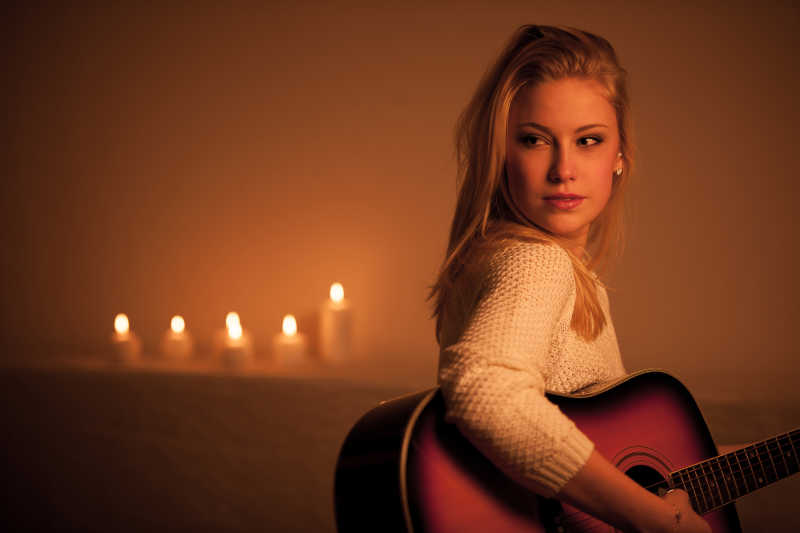 在烛光下弹吉他的金发美女