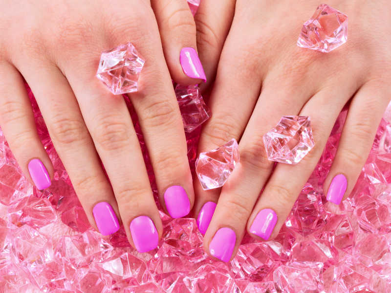 美丽的粉红色的指甲和手的特写