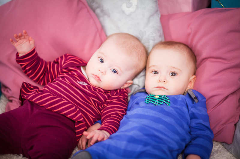 穿着不同衣服躺着看镜头的双胞胎宝宝