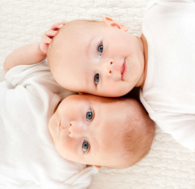 两个躺在白色毛毯上拍照的宝宝