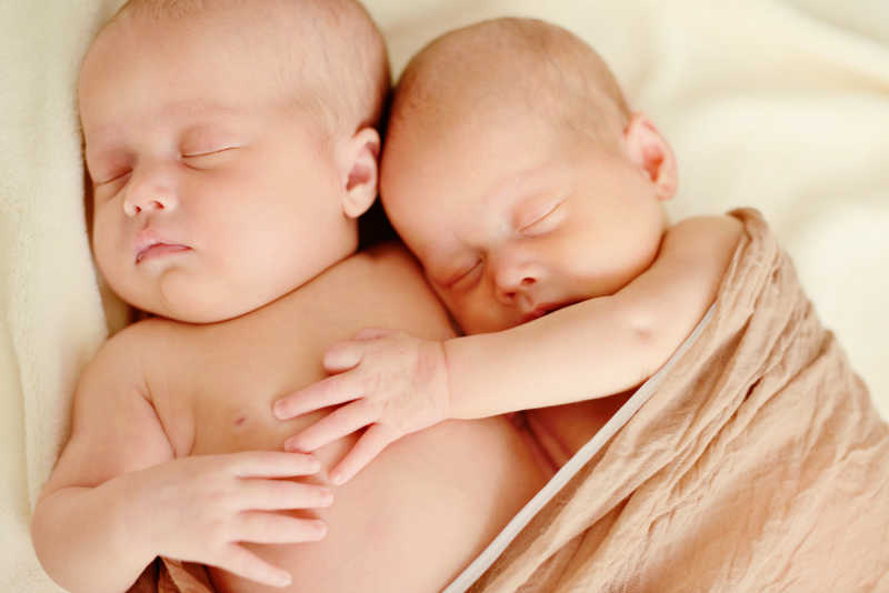 一起睡在柔软棕色包被里的双胞胎宝宝