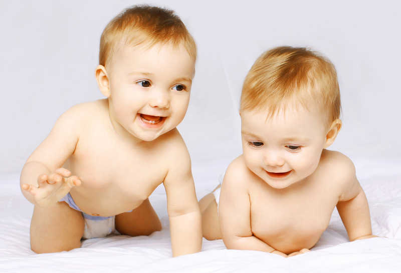 白色床上开心玩耍的双胞胎宝宝