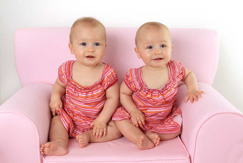 坐在沙发上可爱的穿红衣服的双胞胎宝宝