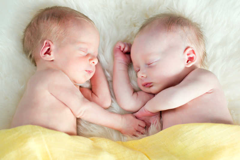 在白色毛毯上睡觉的双胞胎宝宝