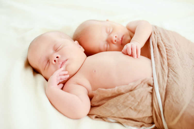 双胞胎宝宝睡在柔软的棕色包被里