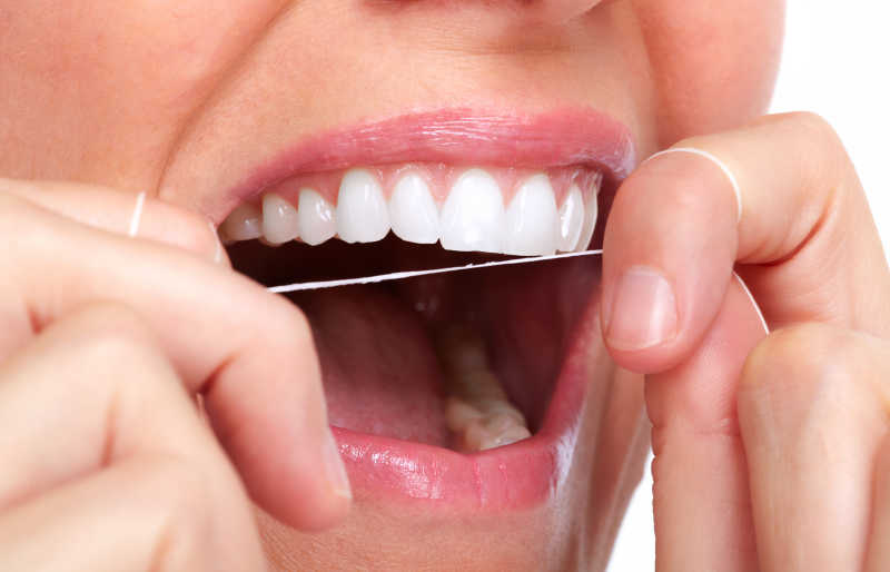 女人在张开嘴巴使用牙线