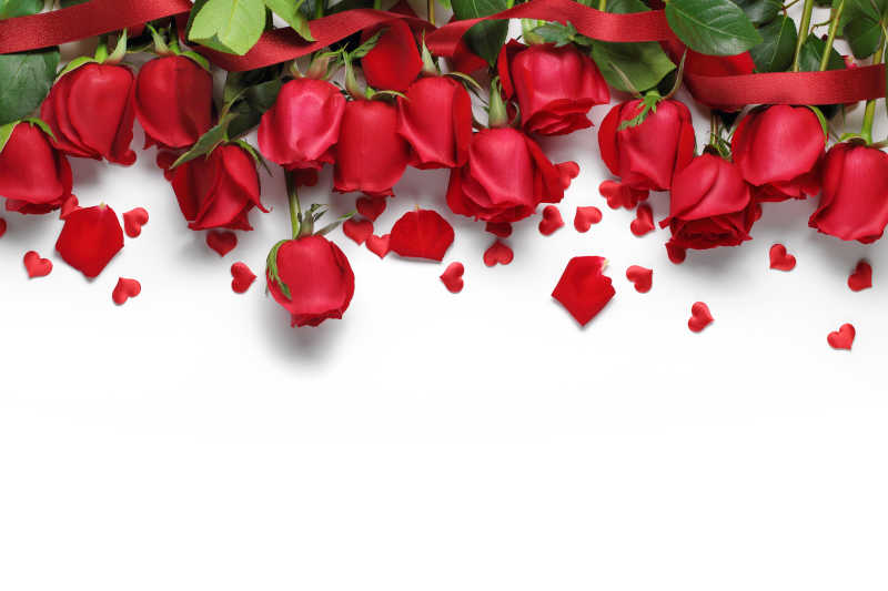 白色背景下的红玫瑰和彩带心形饰物